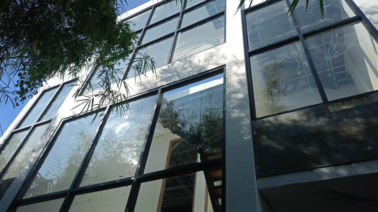 Shakiro Villas under construction — black-frame steel glazing installed, view looking up at the structure